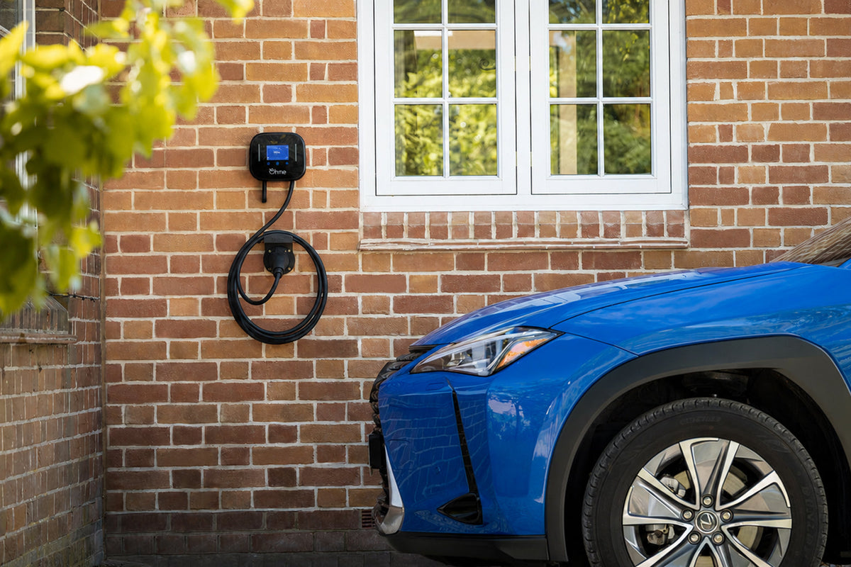 Ein Mann steht in einer Garage und schließt ein Ladekabel an ein weißes Elektroauto von Volkswagen an, das darin geparkt ist.
