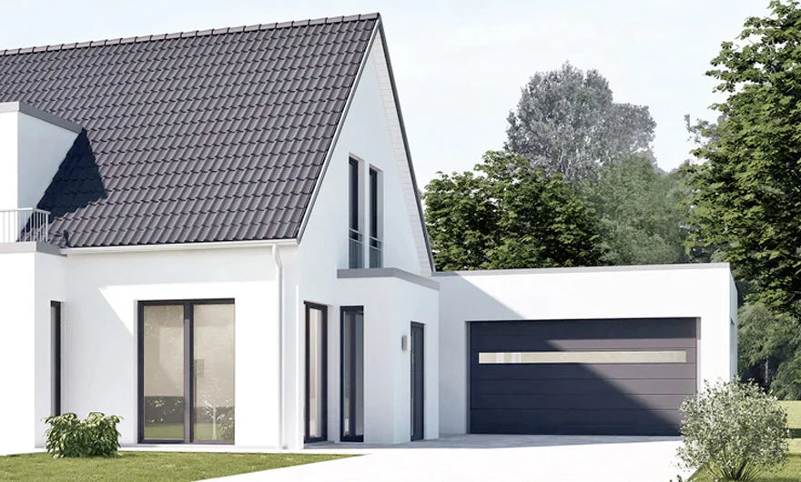 Modernes weißes Haus mit großen Fenstern, einem schrägen dunklen Dach und einer angebauten Garage mit geschlossenem schwarzen Tor, umgeben von Grün unter einem klaren Himmel.
