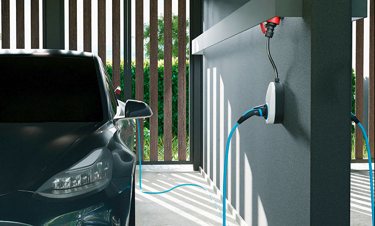 Ein schwarzes Elektroauto, das in einer Garage geparkt ist, wird mit einem blauen Ladekabel an ein an der Wand befestigtes Ladegerät angeschlossen.