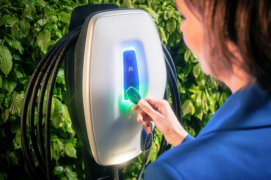 Eine Person hält im Außenbereich eine RFID-Karte an die Ladestation Mennekes AMTRON® 4You 510 C2 von Mennekes und bereitet die Aktivierung vor.