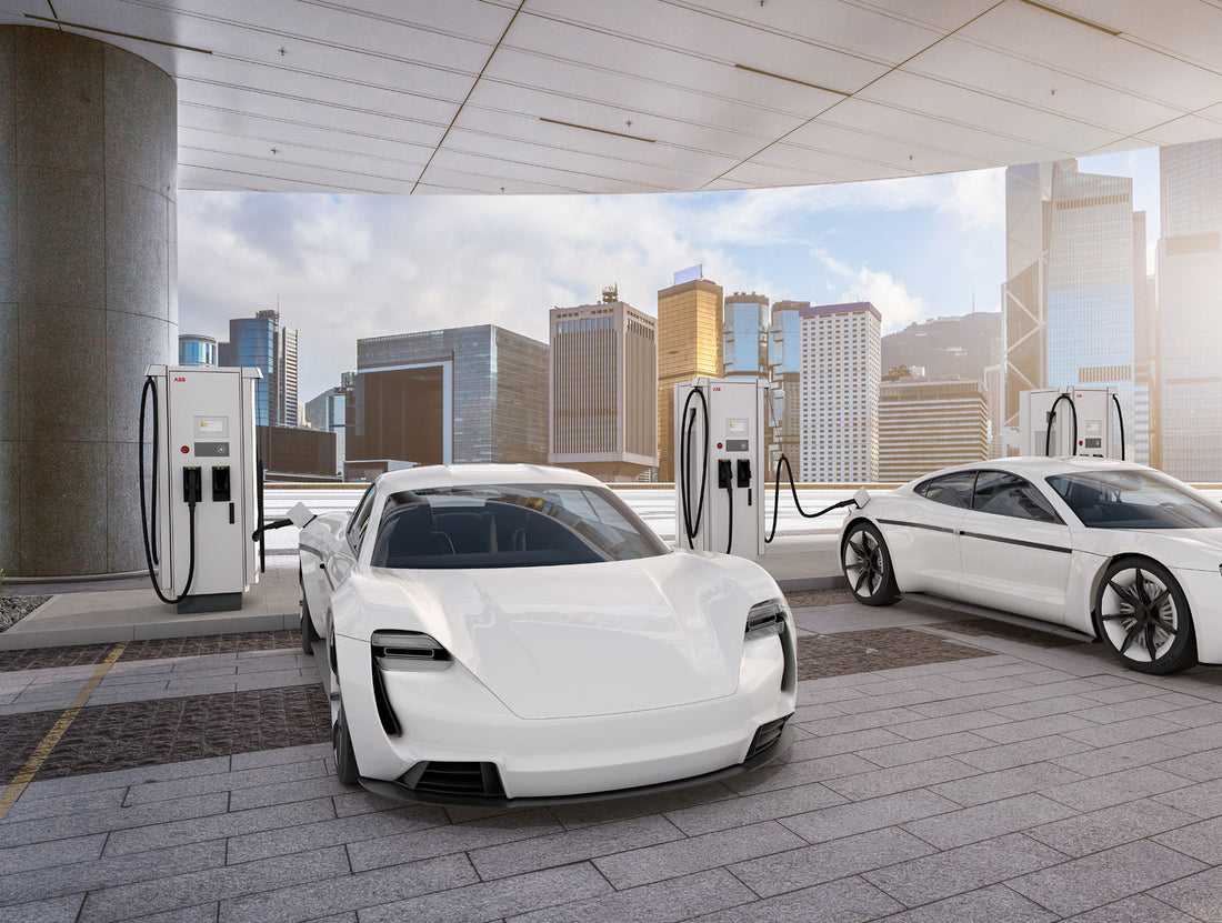 Zwei weiße Elektrofahrzeuge beladen an ABB Terra 94/124/184 Schnellladestationen und profitieren im modernen Stadtbild mit hohen Gebäuden im Hintergrund von der hohen Ladeleistung des ABB Systems.