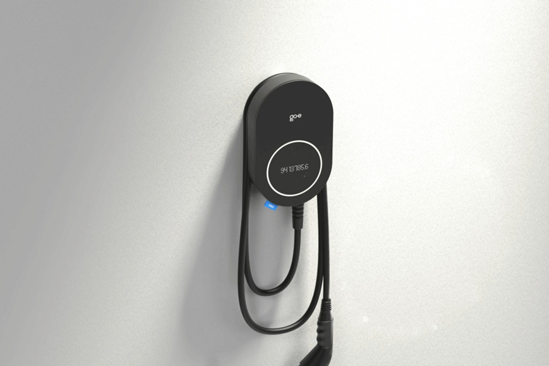 Eine schwarze Ladestation für Elektrofahrzeuge go-e Charger PRO CABLE von go-e, Plug&Charge ready, ist an einer hellen Wand montiert, das Ladekabel ist ordentlich darunter aufgewickelt.