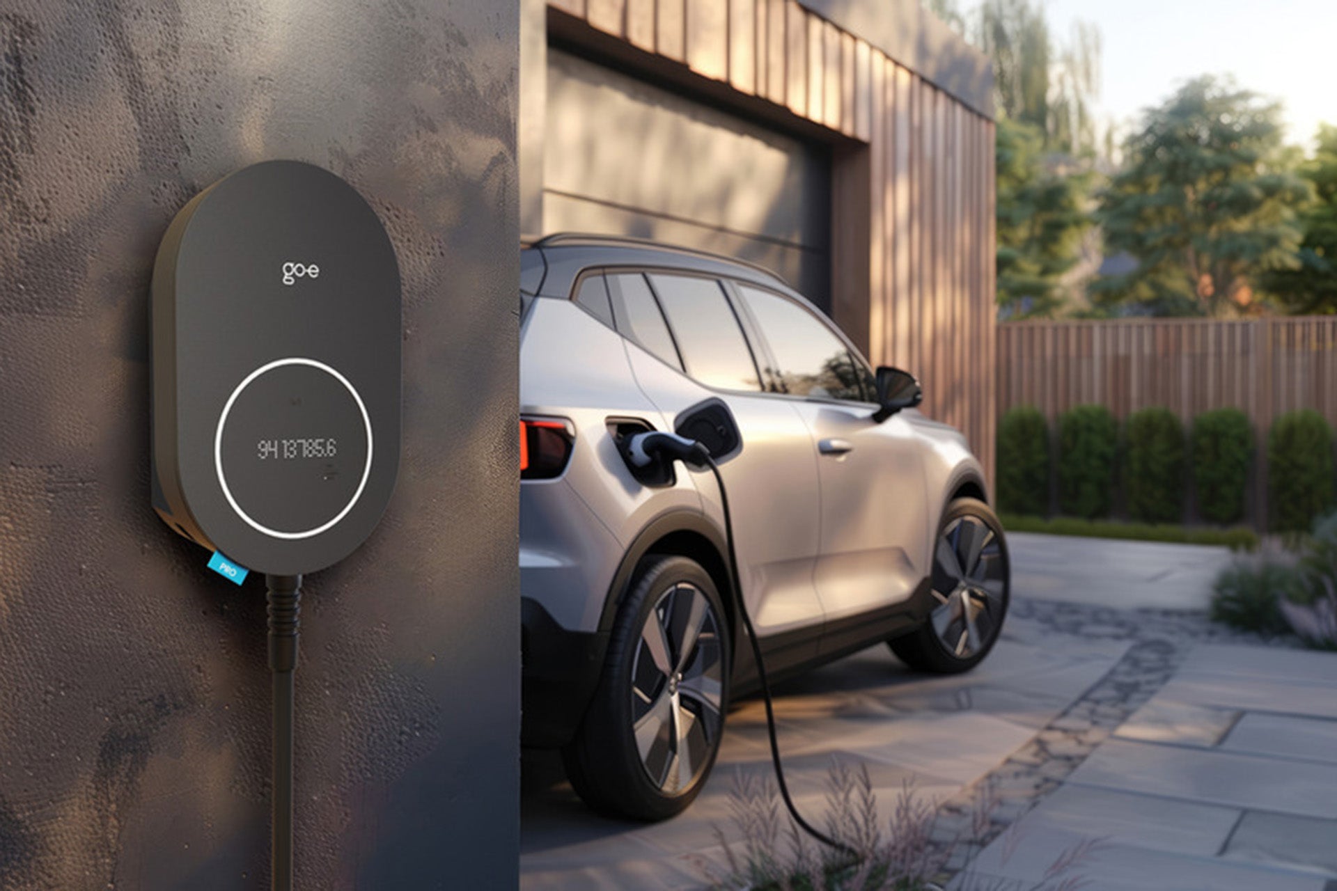 Ein go-e Charger PRO CABLE von go-e ist an einer Außenwand montiert und lädt ein in der Einfahrt eines modernen Hauses geparktes Elektroauto mit skalierbarem Lastmanagement.