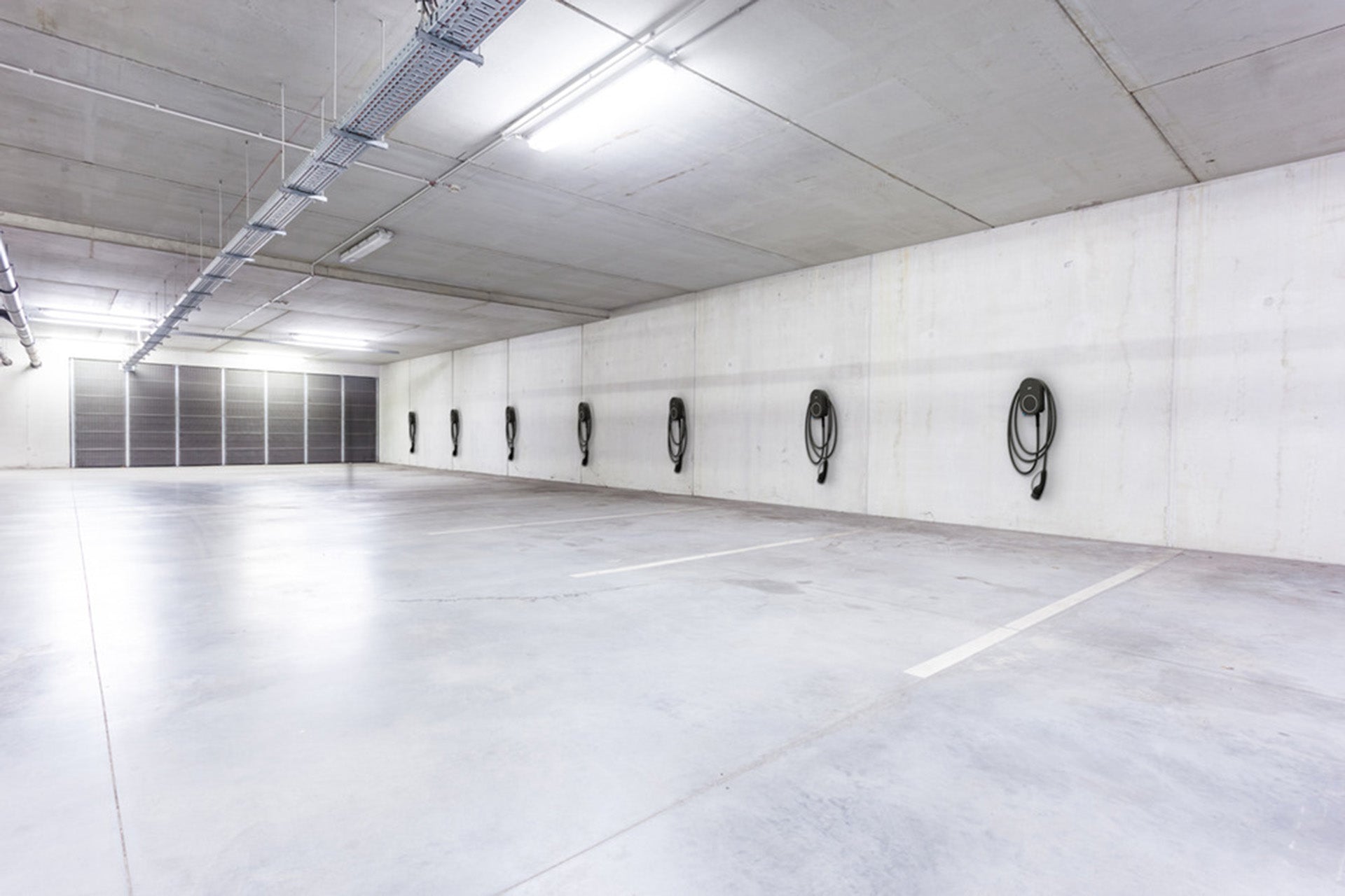 Der go-e Charger PRO CABLE von go-e ist an den großzügigen Betonwänden der Tiefgarage montiert, ideal für PV-Überschussladen und Plug&Charge-fähiges Laden, mit Kabeln fertig für Elektrofahrzeuge.