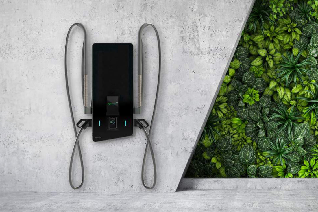 Eine Alpitronic Hypercharger HYC50 DC-Wallbox von Alpitronic mit 50 kW Ladeleistung ist an einer Betonwand neben einem vertikalen Garten mit üppigen grünen Pflanzen installiert.