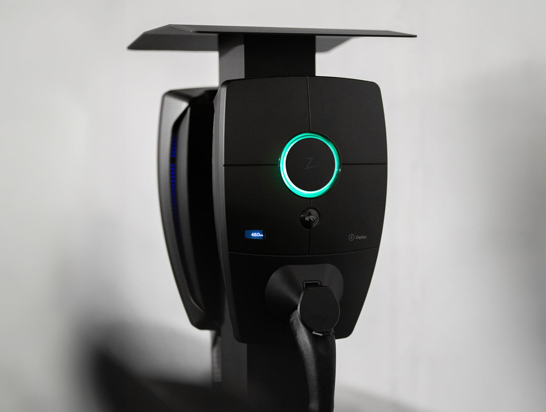 Ein schwarzer Zaptec Pro (22 kW) von Zaptec mit leuchtend grünem LED-Ring, MID-zertifiziertem Energiezähler und angeschlossenem Ladekabel ist an einem Innenpfosten montiert und bietet mehrere Ladepunkte für effizientes Laden von Elektrofahrzeugen.