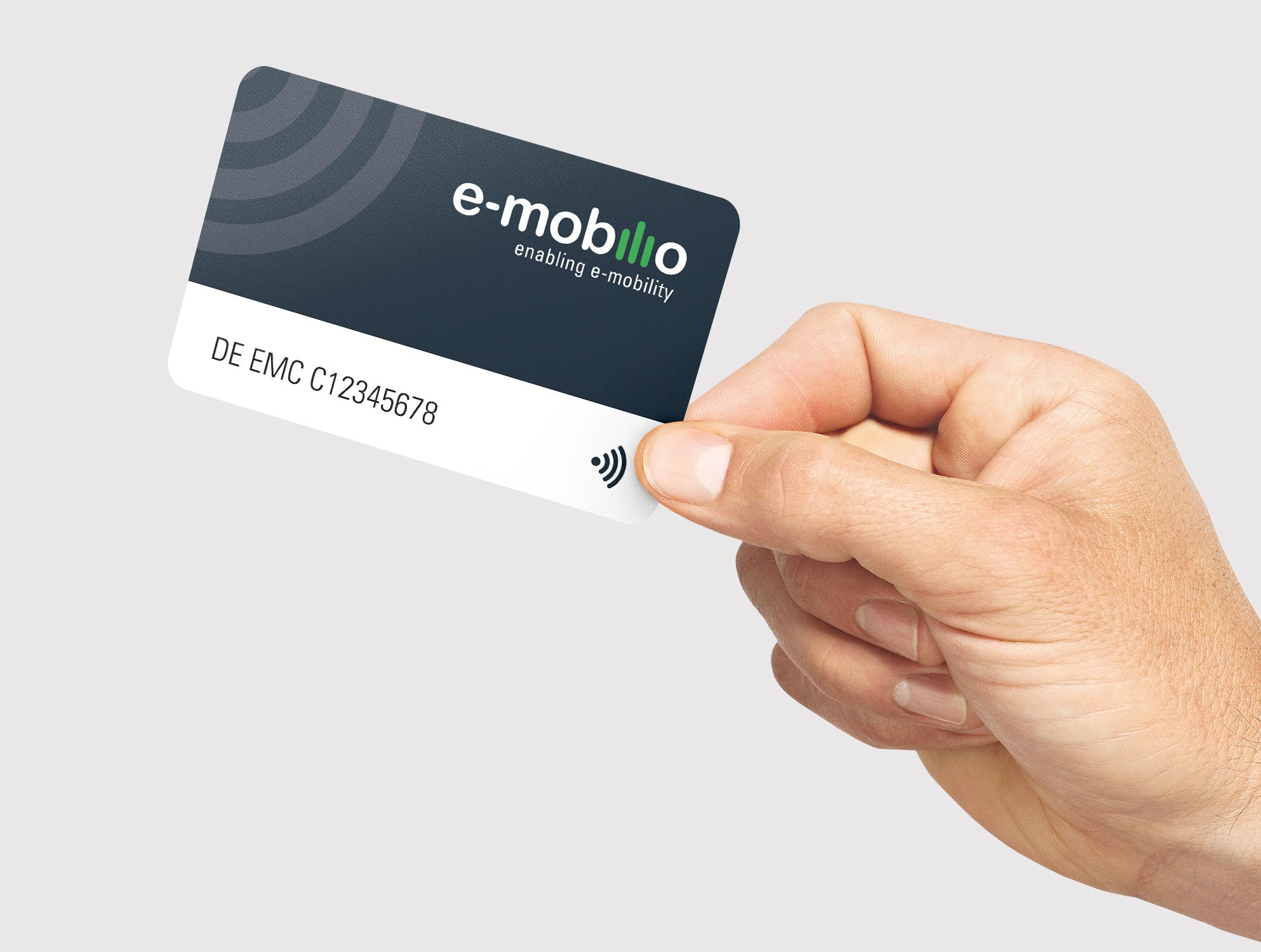 Eine Hand hält eine e-mobilio Ladekarte vom e-mobilio Shop mit der Aufschrift „DE EMC C12345678“, dem E-Mobility-Label und einem Symbol für kontaktloses Bezahlen.