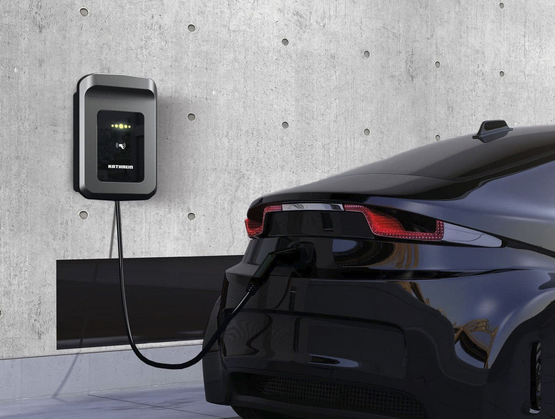 Ein schwarzes Elektroauto wird über eine Kathrein KWB-AC60E Wallbox mit RFID-Autorisierung geladen, die sicher an einer Betonwand montiert ist.