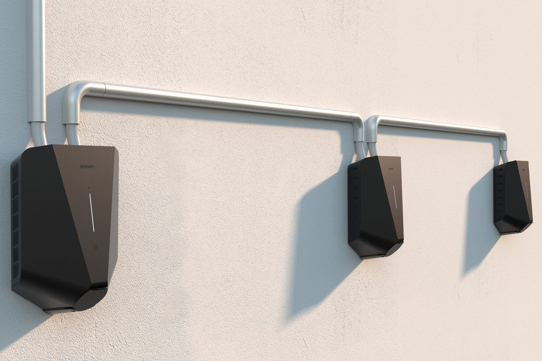 Drei schwarze Easee Charge Max-Wallboxen von Easee werden an der Wand montiert und durch ein Metallrohr an einer Leichtbauwand verbunden. Sie sind bereit, flexiblen Ladestrom für Elektrofahrzeuge bereitzustellen.