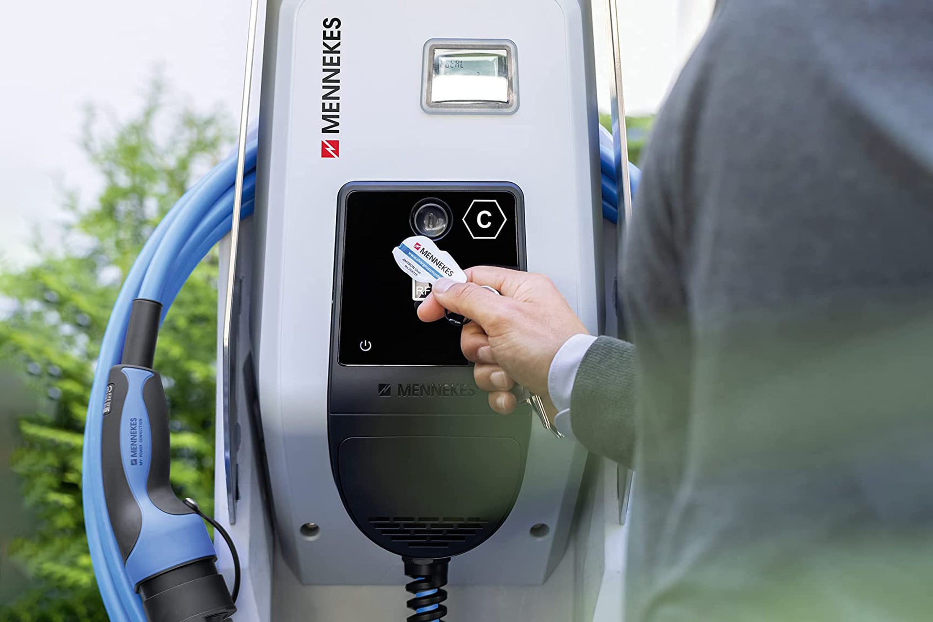 Mittels RFID-Autorisierung erhält eine Person Zugriff auf eine Mennekes AMTRON® Professional Ladestation, an deren Seite ein Ladekabel angebracht ist.