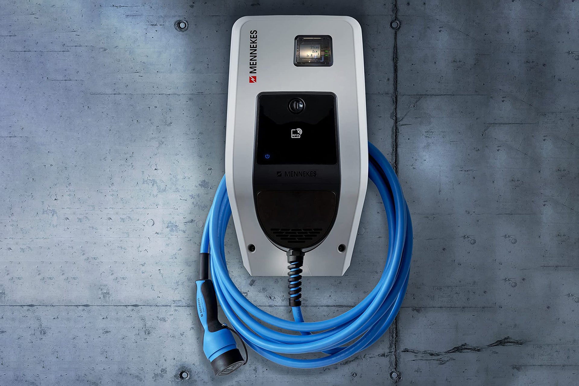Die Mennekes AMTRON® Professional, eine wandmontierte Ladestation für Elektrofahrzeuge von Mennekes, verfügt über ein blaues Ladekabel und RFID-Autorisierung für sicheren Zugriff und wird an einer Betonwand befestigt.