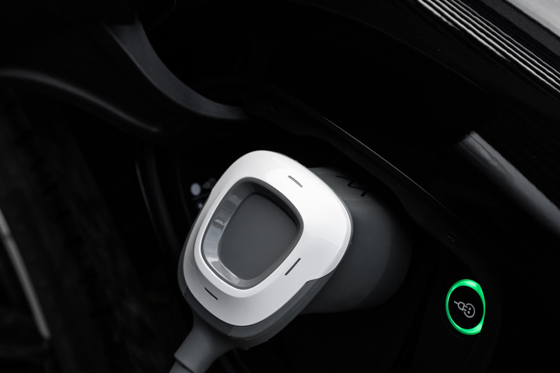 Ein weißes Charge Amps Halo-Ladegerät für Elektrofahrzeuge von Charge Amps aus recyceltem Aluminium ist eingesteckt und eine grüne Kontrollleuchte leuchtet.