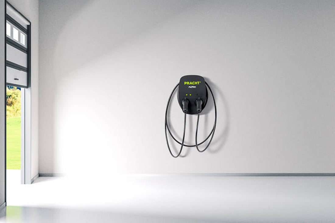 Eine Pracht Alpha XT von Pracht, eine schwarze Wandladestation mit IP65-Schutz und zwei Kabeln, ist an einer schlichten weißen Wand in einem hellen, leeren Raum mit offener Tür nach draußen installiert.