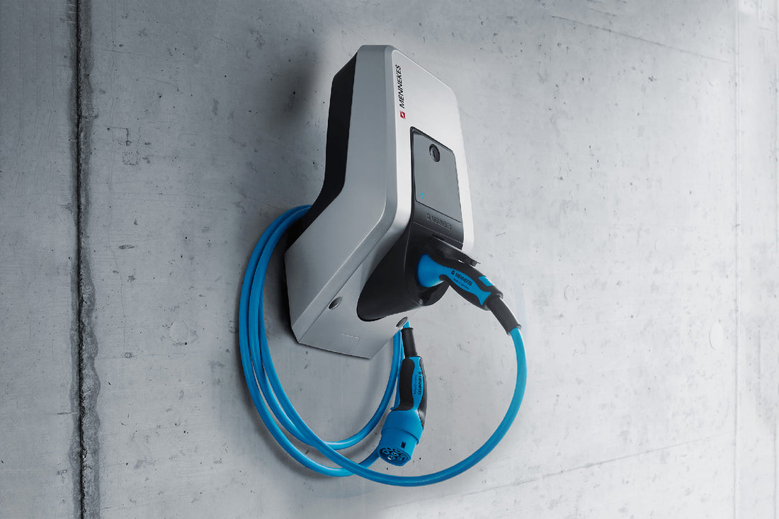 Die Mennekes AMTRON® Charge Control ist eine wandmontierte EV-Ladestation von Mennekes mit einem blauen Spiralkabel und dynamischem Lastmanagement, die an einer glatten Betonwand installiert wird.