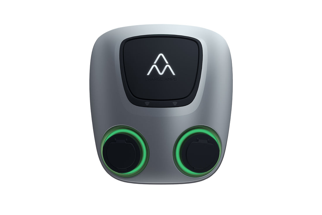 Die Charge Amps Aura von Charge Amps ist eine duale Ladestation für Elektrofahrzeuge mit zwei grün beleuchteten Ladepunkten, RFID-Autorisierung und einem schwarzen Logofeld auf einem eleganten silbernen Gehäuse.