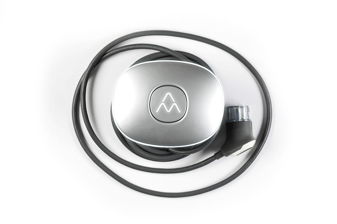 Der Charge Amps Halo von Charge Amps ist eine silberne Ladestation aus recyceltem Aluminium mit einem gewickelten schwarzen Kabel und Stecker vor einem weißen Hintergrund.