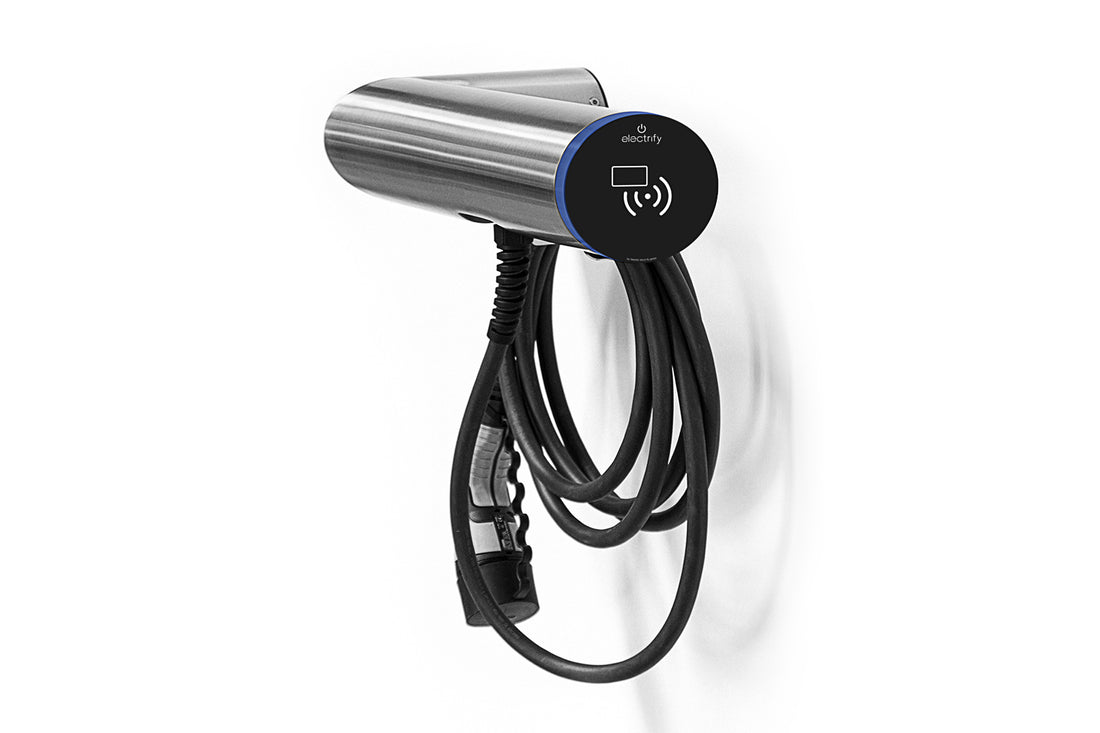 Eine Edelstahl-Ladestation hesotec electrify eBox wr30 Smart mit WLAN und LAN ist an einer weißen Wand montiert, das Kabel ist ordentlich darunter aufgewickelt.